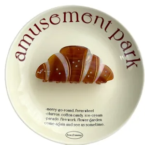 French croissant hair claw clip with diamonds and amber texture on a vintage porcelain plate