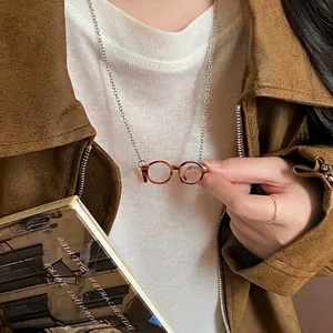 Miniature brown tortoise shell eyewear necklace with silver chain on model