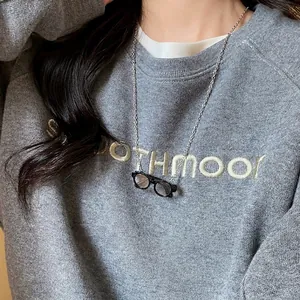 Miniature glasses pendant necklace in silver chain on a casual grey sweatshirt