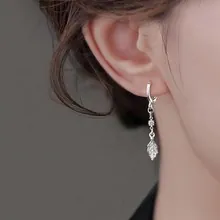 Detail of silver hoop earring with sparkling zircon star and textured metal leaf on model