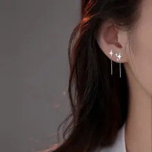 Close-up of star and moon tassel chain earrings worn on ear with elegant silver finish