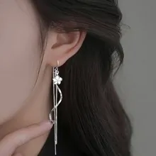Detailed close-up of silver long tassel earrings with flower charm and metal chains