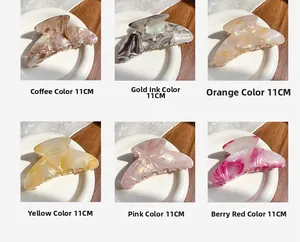 Detail view of 11cm large acetate hair claws in six colors on white ceramic plates