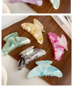 Detailed top view of large marble texture hair claws in various vibrant colors on wood