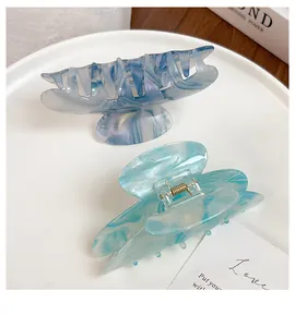 Detail of acetate hair claws in marble patterns on a white minimalist display tray
