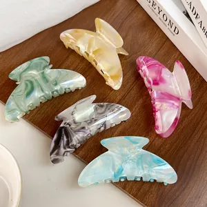 Elegant marble texture acetate hair claws in various colors arranged on a wooden table