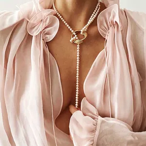 Elegant pearl necklace with golden rings worn on a model with a soft pink chiffon blouse