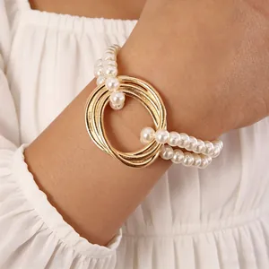 Elegant double-layer pearl bracelet with interlocking gold rings on a model wrist
