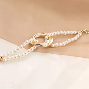 Detail of elegant pearl bracelet featuring golden interlocking rings and lobster clasp