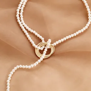 Detail view of pearl fringe necklace with golden triple ring clasp on soft fabric