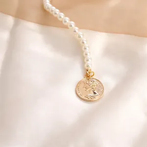 Close-up of pearl necklace featuring a vintage gold coin pendant with portrait relief
