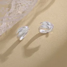 Close-up of silver feather rings with adjustable open band and detailed metal textures
