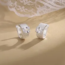 Detail of silver textured ear cuffs with sparkling square zircon on beige lace background