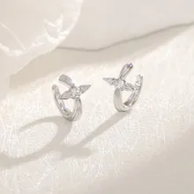 Macro shot of silver four-pointed star ear cuffs featuring central crystal on white background