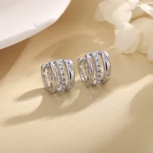 Close-up of silver layered hoop earrings with sparkling cubic zirconia on a warm fabric