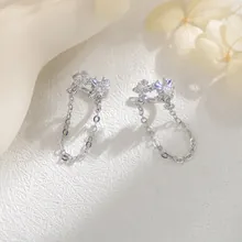 Close-up of elegant silver bow earrings with sparkling zircons and dangling chains