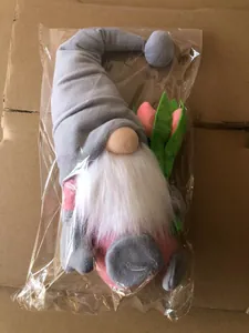 Close-up of a plush gnome with pink tulip and gray hat in transparent protective packaging