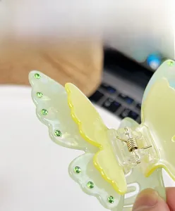 Detailed close-up of translucent green acrylic butterfly hair claw clip with rhinestones