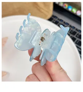 Detailed close-up of light blue pearlescent butterfly hair claw clip with metal spring