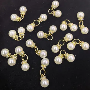 Close-up of double ABS pearl pendants with gold ring connectors and small rhinestones