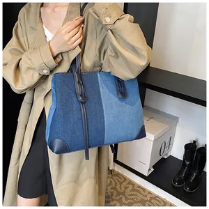 Detailed shot of large denim tote bag paired with a stylish khaki trench coat on shoulder