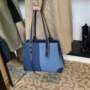 Large denim patchwork tote bag with leather handles shown in a lifestyle street fashion setting