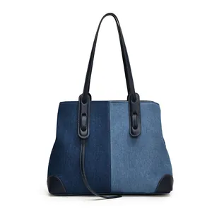 Large denim tote bag with blue color-blocking and leather handles on white background