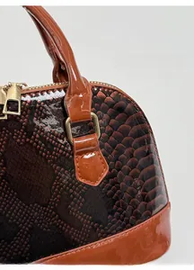 Detailed view of the shiny brown snakeskin embossed patent leather with gold hardware