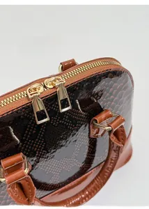 Detailed macro view of golden double zippers and brown snakeskin pattern patent leather