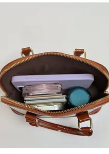 Internal storage view of patent leather handbag showing capacity for phone and makeup