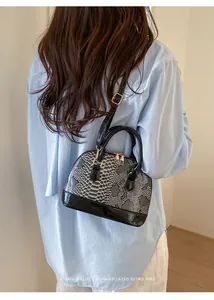 Detailed back view of snakeskin pattern shell bag with golden hardware on a model