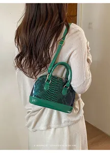 Detail of dark green snakeskin texture and glossy patent leather on a retro shell bag