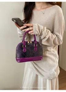 Detail of purple faux snakeskin shell bag featuring gold zippers and patent leather finish