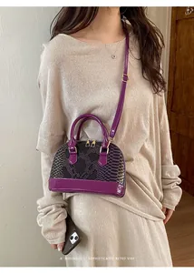 Detail of purple snakeskin embossed shell bag with glossy patent leather finish and gold zipper