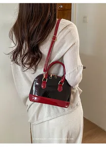 Model view of a vintage patent leather shell bag with red and dark contrast details