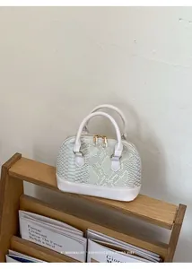 Detail of mint green snake skin texture shell bag with white patent leather and gold zipper