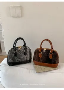 Detail of snake pattern shell bags in black and brown with golden hardware zippers