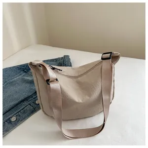 Detailansicht der beigen Nylon-Halbmondtasche mit verstellbarem Riemen auf Stoff