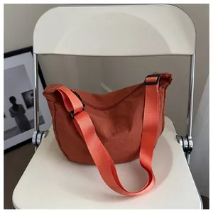 Halbmondtasche aus karamellfarbenem Nylon mit verstellbarem Riemen auf weißem Stuhl