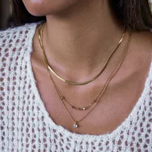 Primo piano della collana a tre strati in acciaio dorato con cristallo su modella