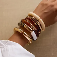 Dettaglio di bracciali bohémien sovrapposti con resina leopardata e catene in metallo dorato