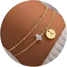 Dettaglio del bracciale dorato a strati con ciondolo lettera A e fiore scintillante