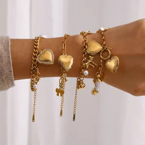 Dettaglio di un set di bracciali dorati con ciondoli a cuore e perle sintetiche