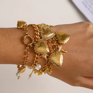 Dettaglio del bracciale multistrato dorato con cuori, perle e ciondoli a farfalla
