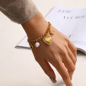 Dettaglio di un bracciale in acciaio al titanio dorato con ciondoli a cuore e perle al polso