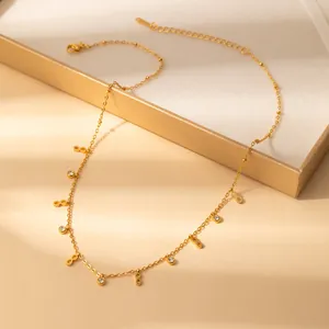 Detail of gold infinity charm necklace with zircon accents on a beige jewelry case