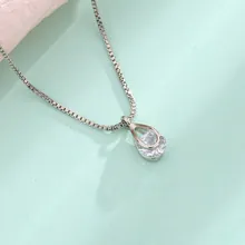 Detail of water drop pendant with cubic zirconia and cross chain in golden finish