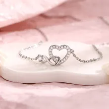 Detailed close-up of heart and infinity pendant necklace with cubic zirconia on stone