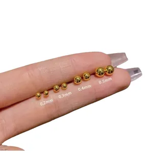 Mini golden frosted round bead stud earrings in 0.2mm to 0.5mm sizes shown on fingertip