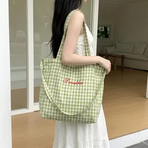 Detailed view of green gingham canvas tote bag with red Soxakka script embroidery